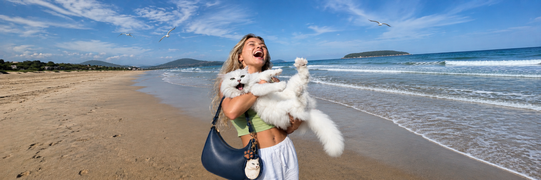 A woman holding her fluffy white dog on a beach, showcasing a Memopaw custom pet bag charm attached to her shoulder bag as a personalized daily keepsake.