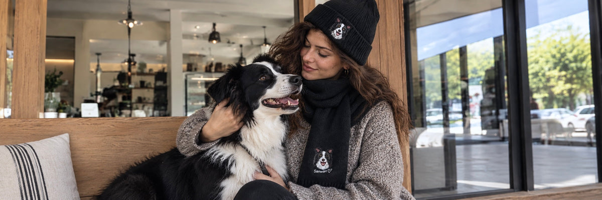 Woman holding a black and white dog on a sofa in a cozy living room, showcasing custom pet photo gifts.