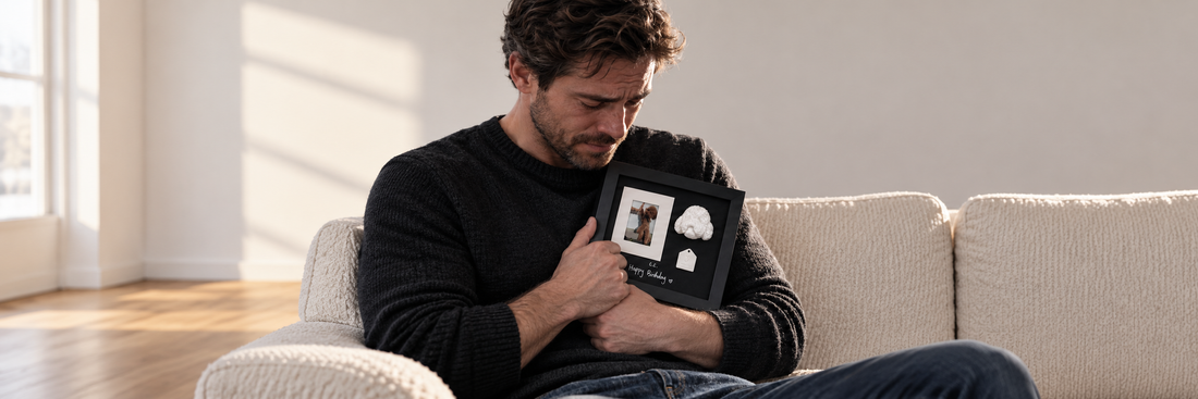 A man comfortably sitting on a couch, gently holding and comforting his cat.