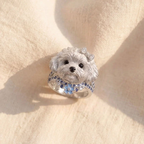 Silver dog-shaped ring with gemstones on a beige fabric background