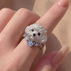 Silver dog-shaped ring on a finger with a soft background