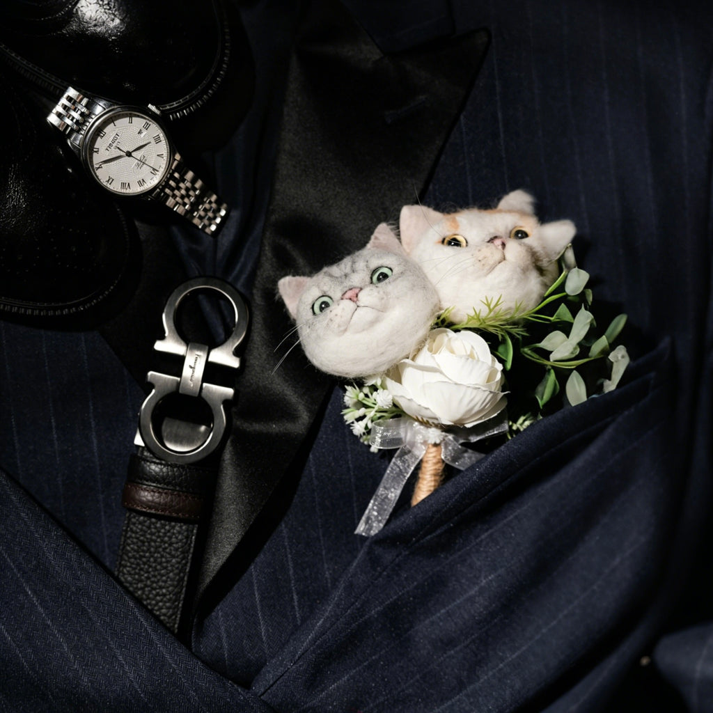 Two small cats with a flower arrangement on a dark suit jacket.