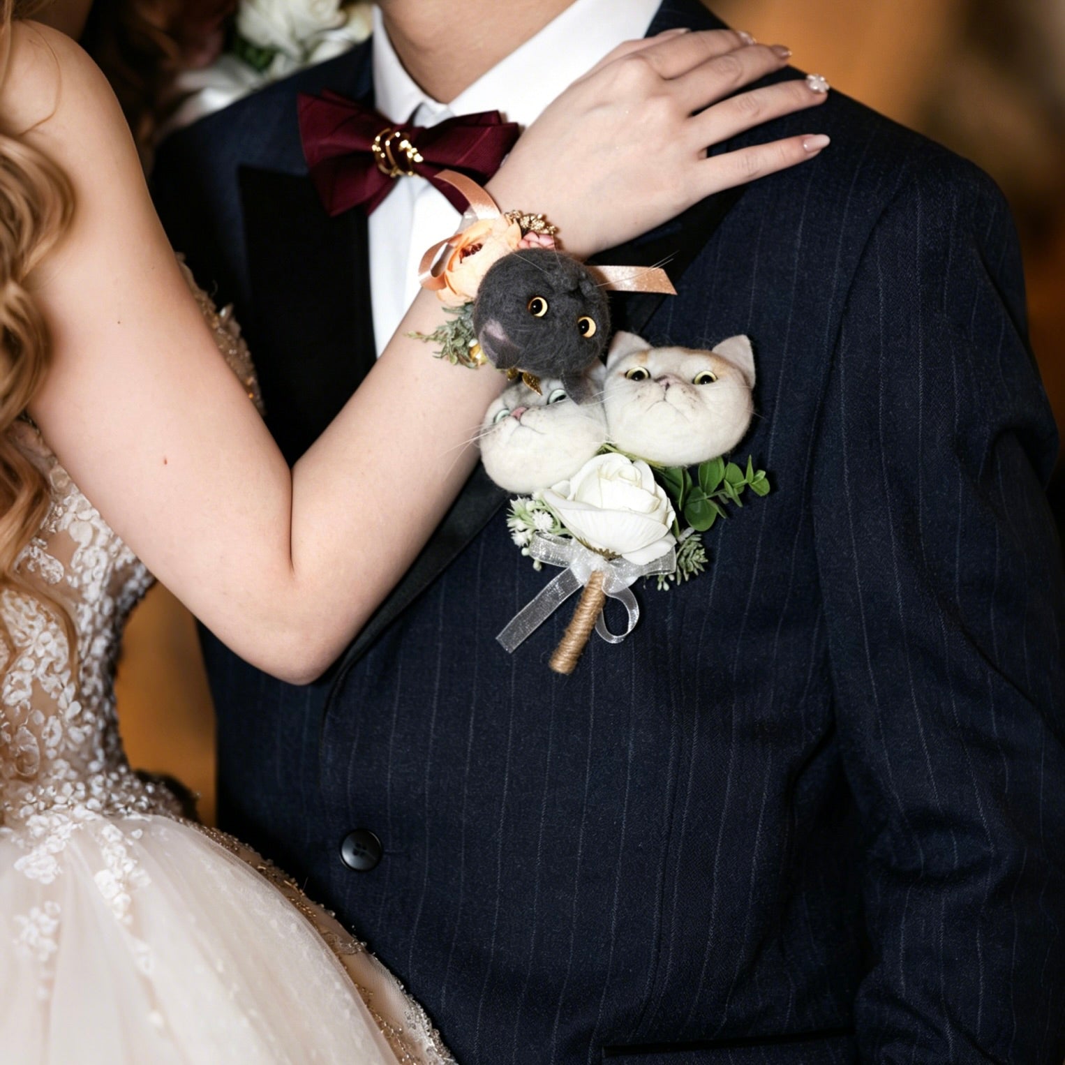 Person wearing a boutonniere with a small stuffed animal and flowers on a dark suit.