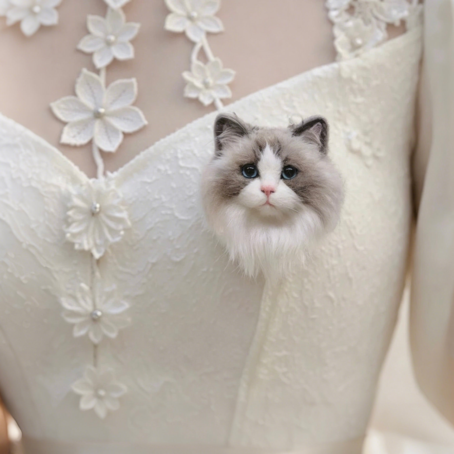Cat sitting on a white wedding dress with floral embroidery