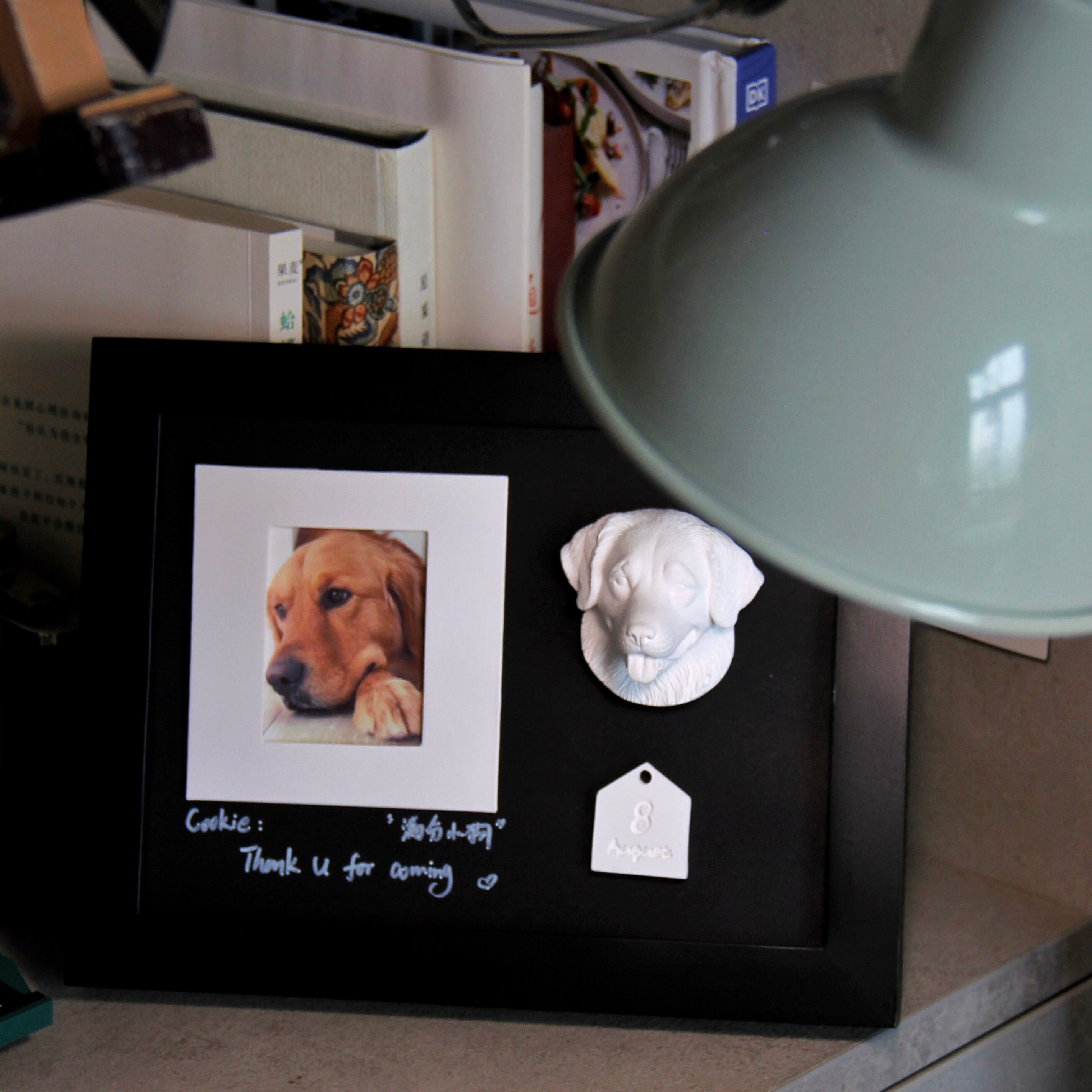 Black frame with a photo of a dog and a small white dog figurine on a surface.