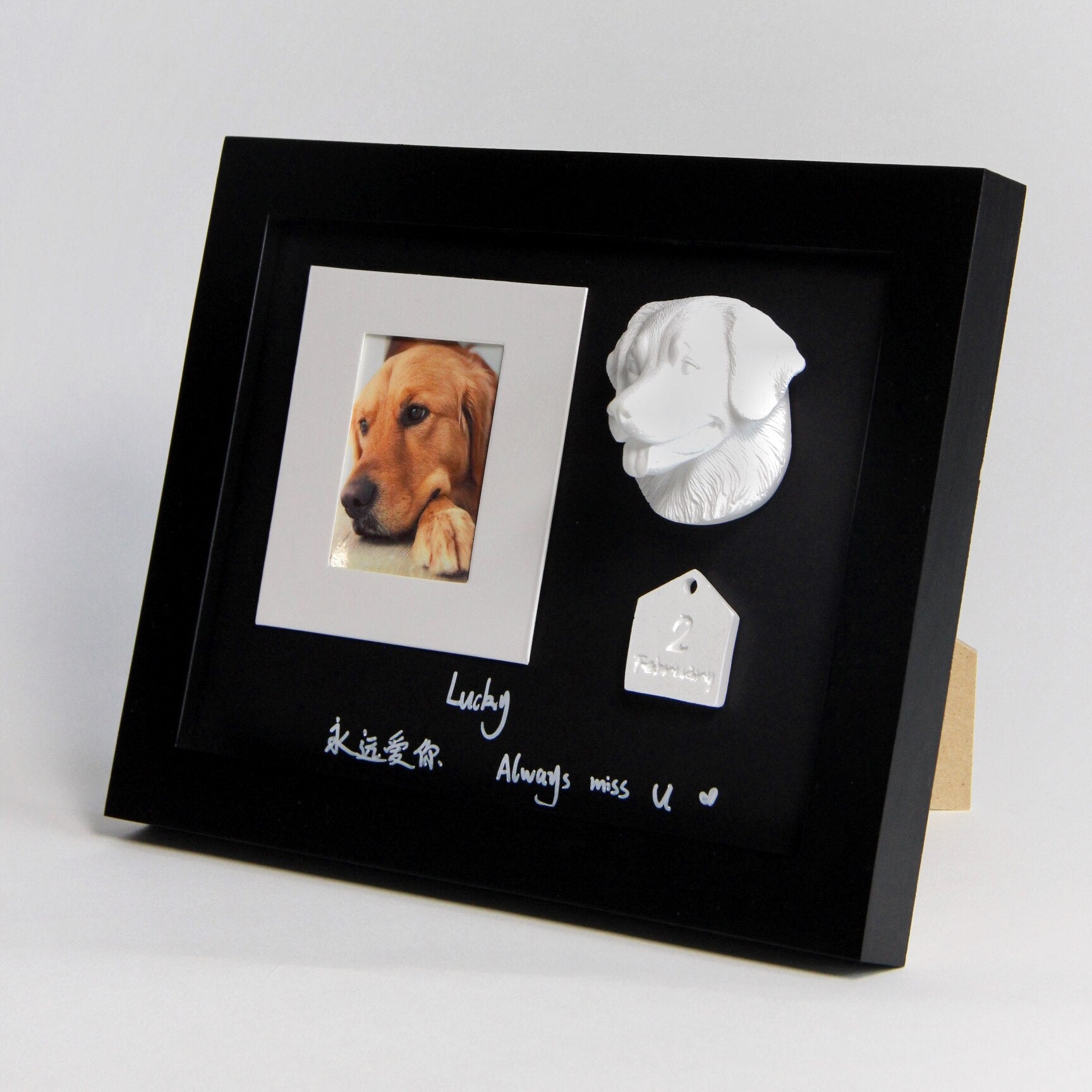 Black framed memorial with a photo of a dog, a sculpture, and text on a white background