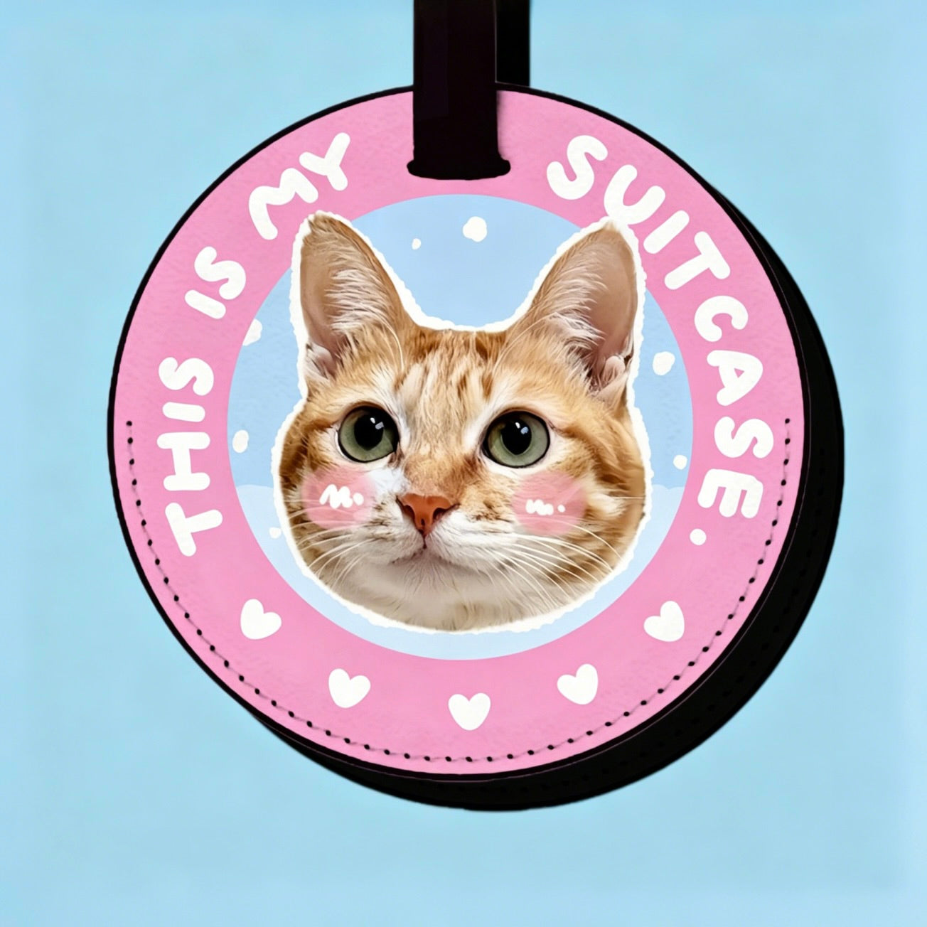 Round pink luggage tag with a cat's face and 'This is my suitcase' text on a light blue background