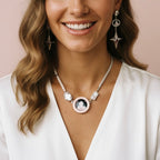 Woman wearing a necklace with a pendant and matching earrings against a neutral background