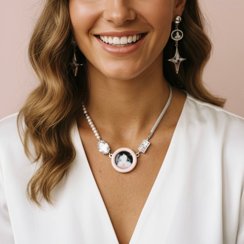 Woman wearing a necklace with a pendant and matching earrings against a neutral background