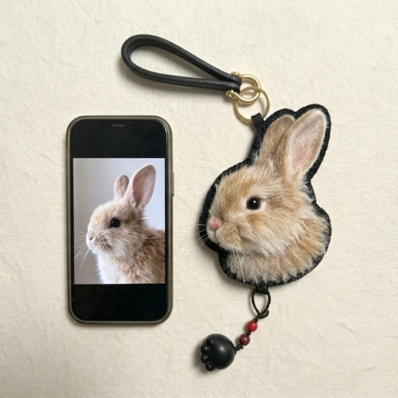 Phone with rabbit-themed case and matching keychain on a beige background