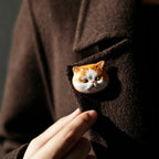 Cat-shaped brooch on a coat with a hand adjusting it