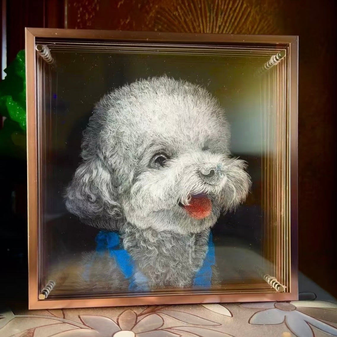 Framed picture of a small dog with a blue collar on a decorative surface.