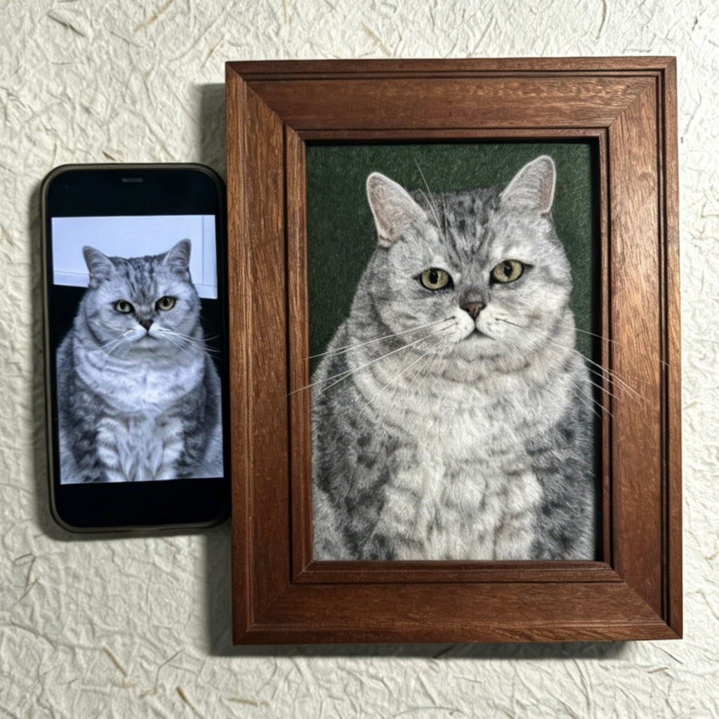 Framed portrait of a cat next to a smartphone displaying the same image on a textured wall.