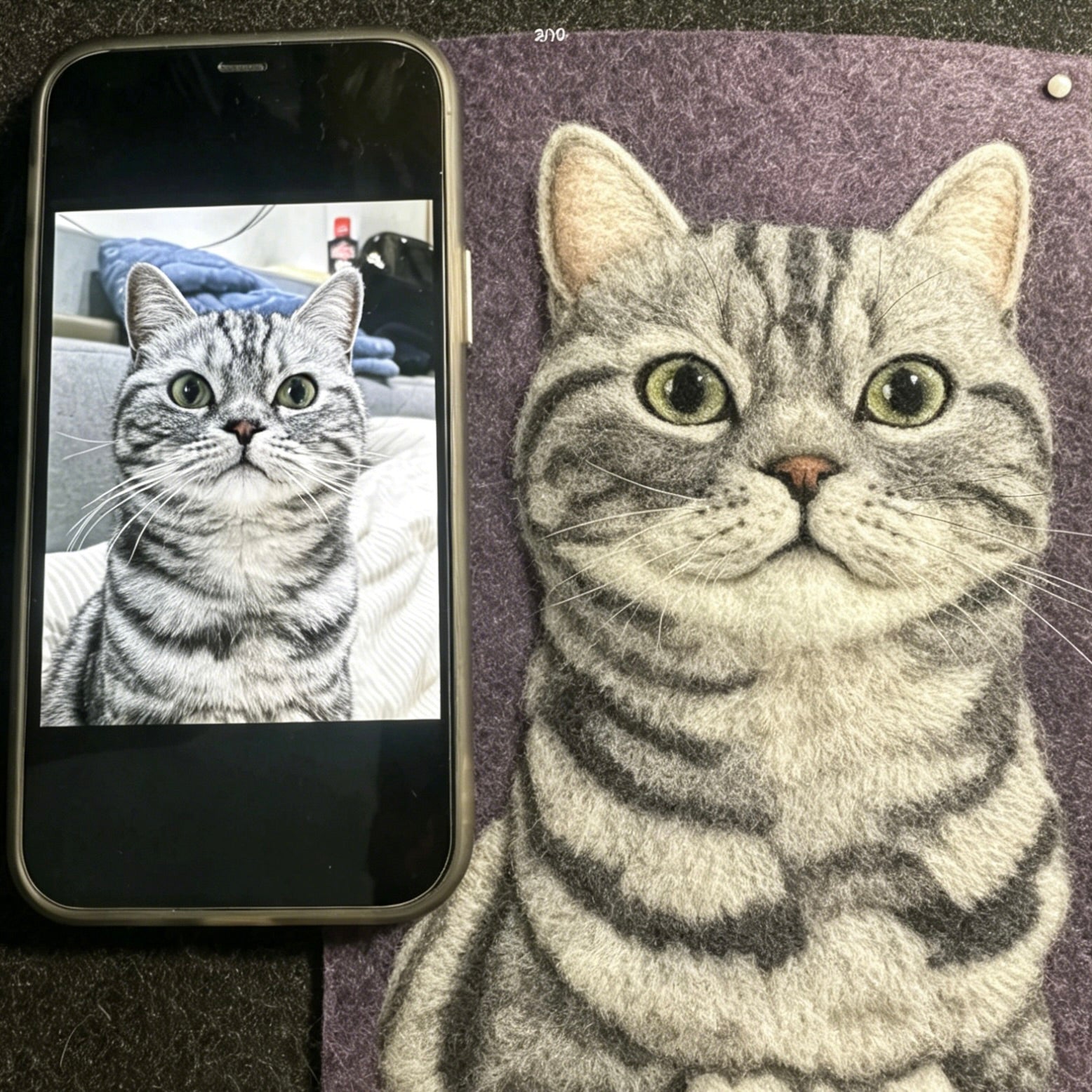 Realistic drawing of a cat next to a smartphone displaying a photo of a cat.