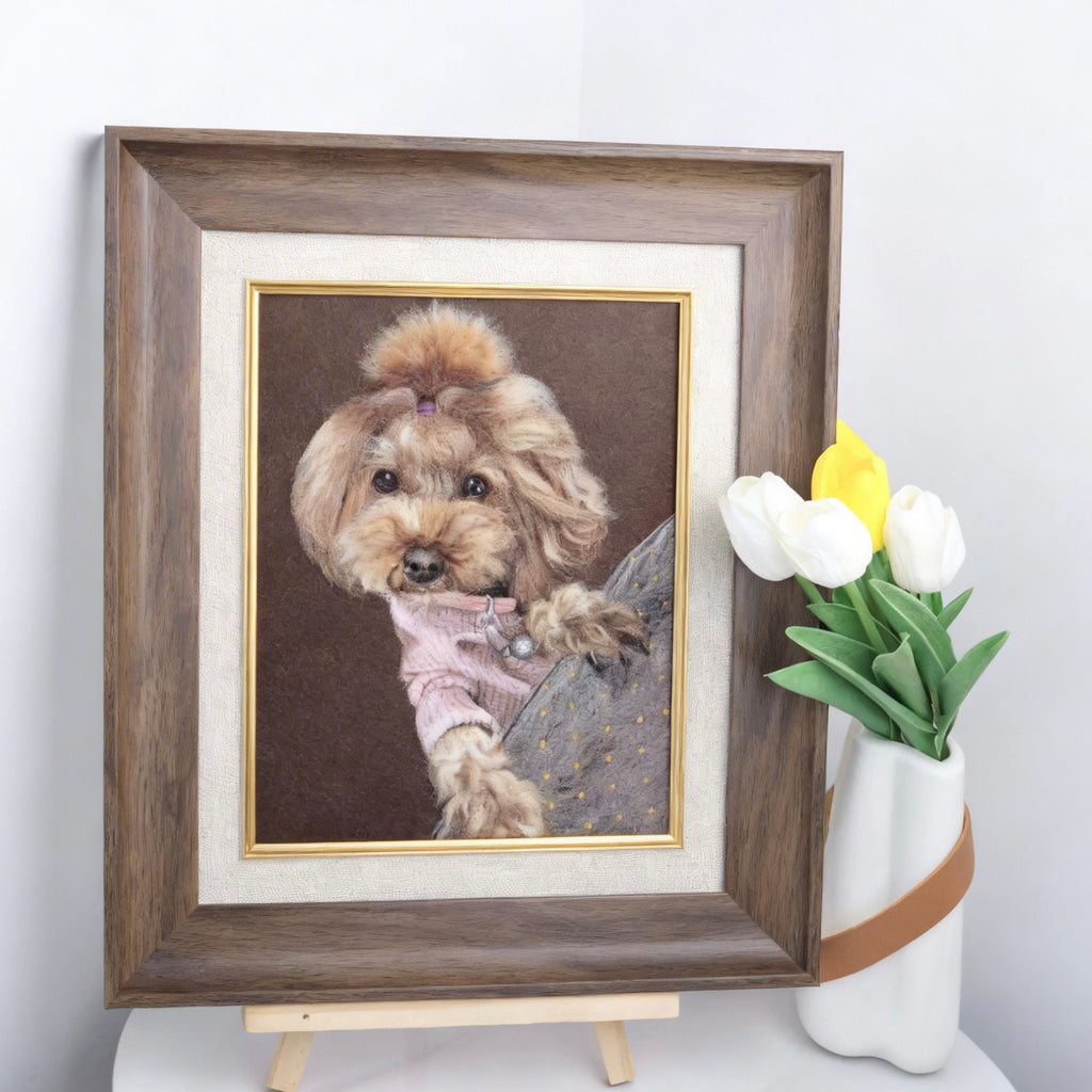 Framed portrait of a dog wearing a pink sweater on a white surface with a vase of tulips.