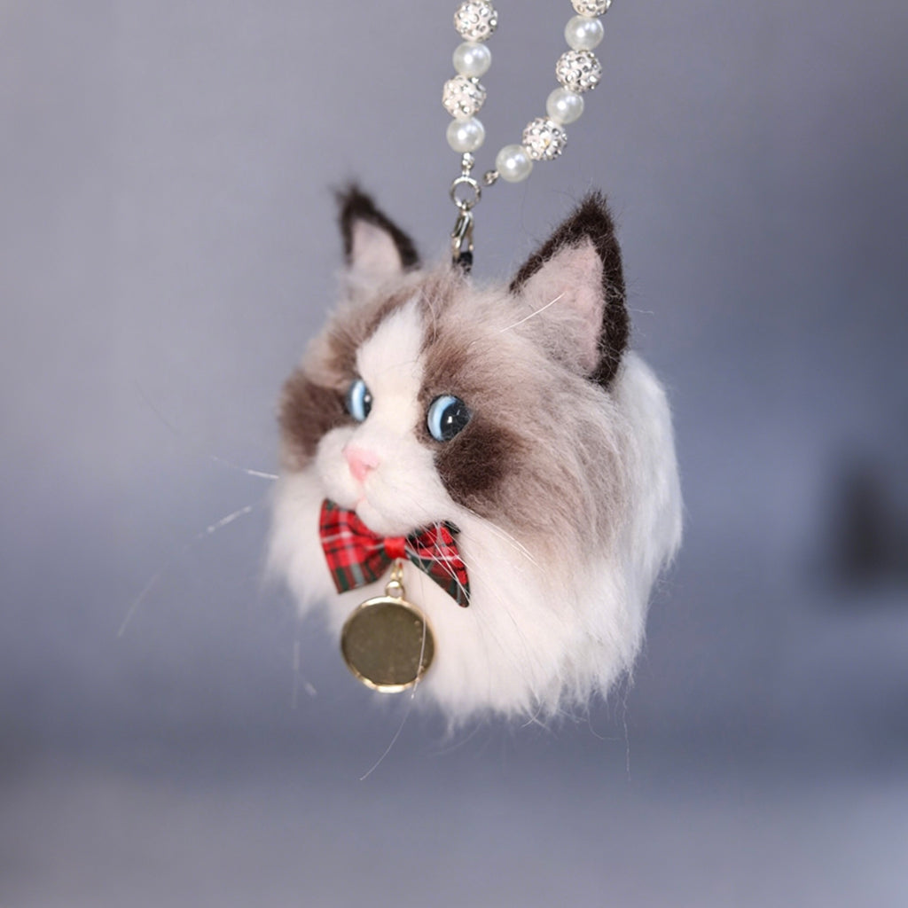 Cat-shaped keychain with a plaid bow tie and bell on a gray background