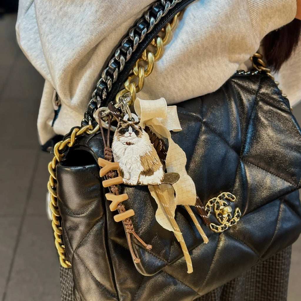 Black quilted handbag with decorative charms and a gold chain strap.