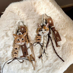 Cat-themed keychains with scarves on a fluffy white surface