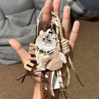 Hand holding a decorative keychain with an owl design against a blurred background
