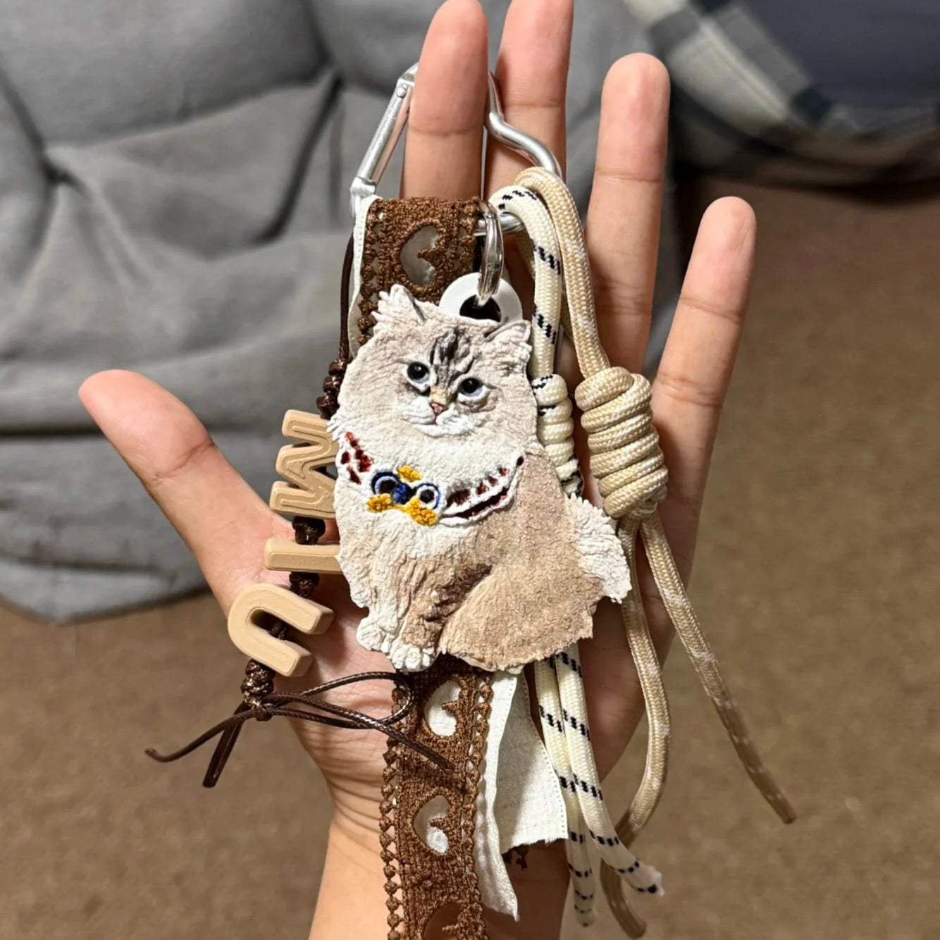 Hand holding a decorative keychain with an owl design against a blurred background