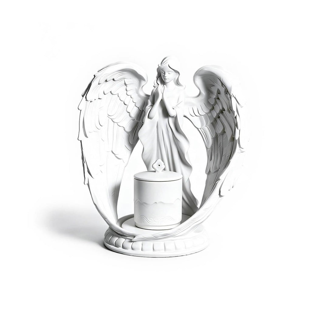 White angel figurine with wings spread holding a candle on a white background