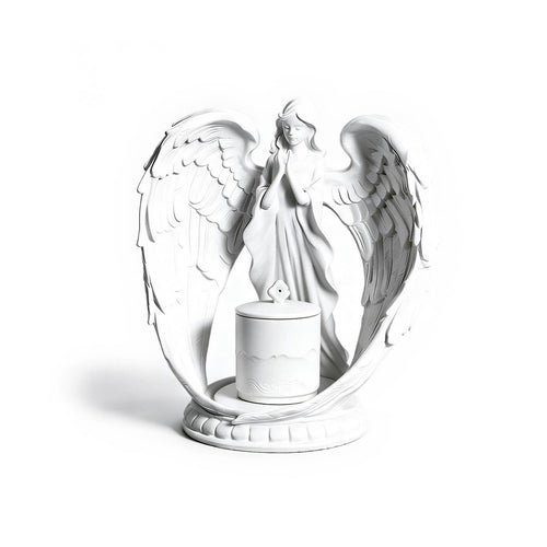 White angel figurine with wings spread holding a candle on a white background