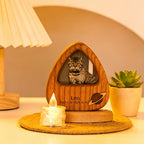 Wooden pet memorial with a photo of a cat, placed on a table with a candle and plant.
