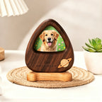 Wooden pet memorial with a photo of a dog on a table with a lamp and plant in the background.
