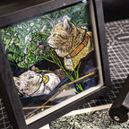 Framed artwork of two cats in a garden setting with flowers and leaves.