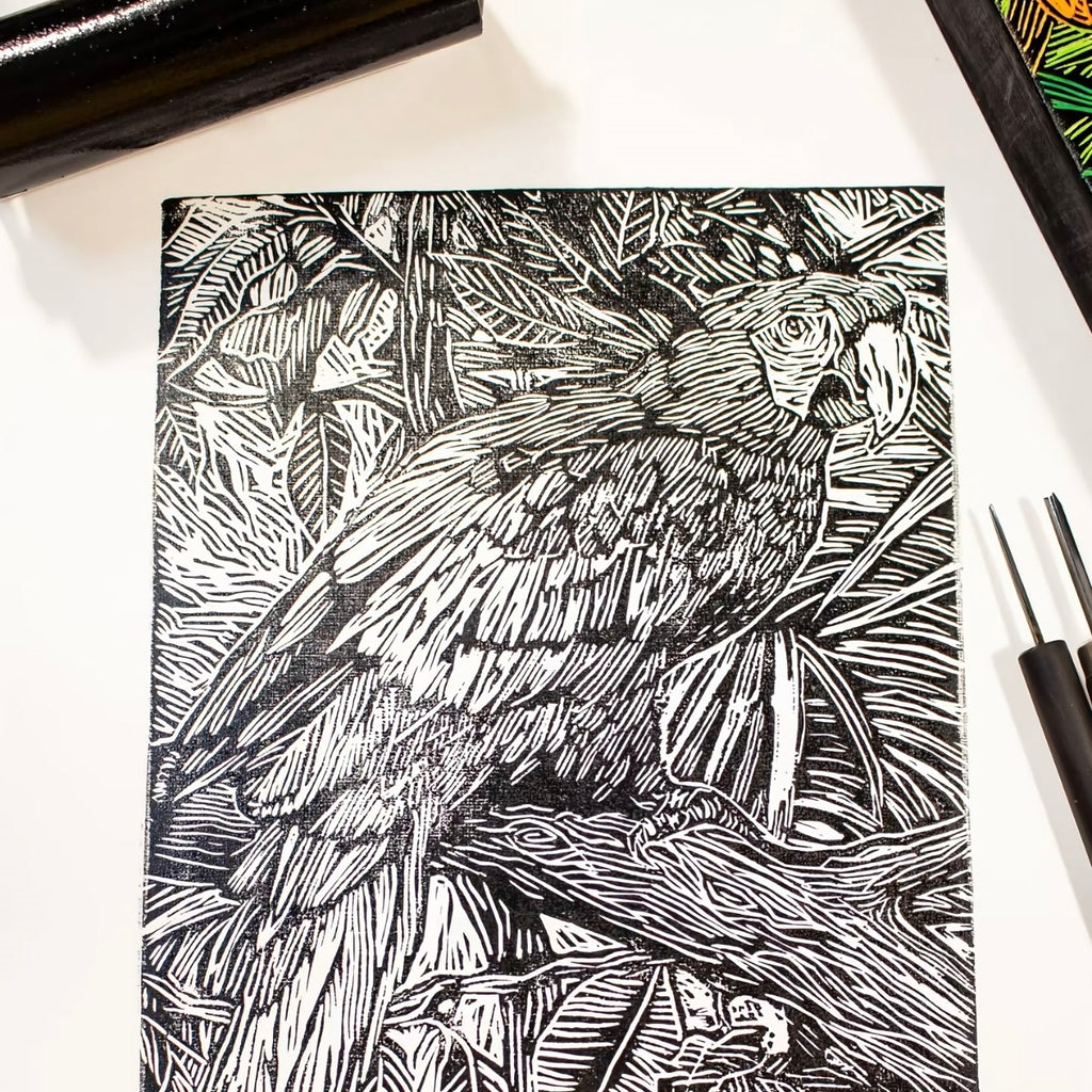 Black and white illustration of a parrot on a notebook cover with drawing tools.