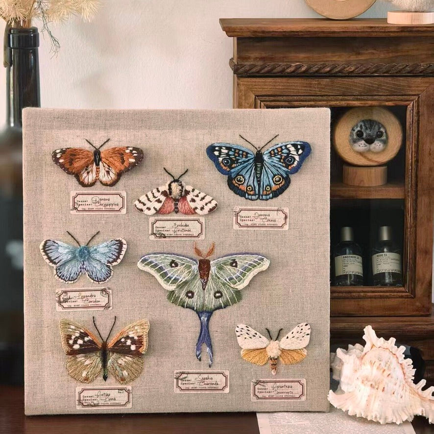 Detailed close-up of a custom butterfly embroidery pin with blue and beige details, resting on an engraved wooden keepsake base.