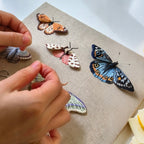 Hand embroidery process showing realistic thread texture of a custom butterfly brooch, being delicately adjusted with a traditional needle tool.