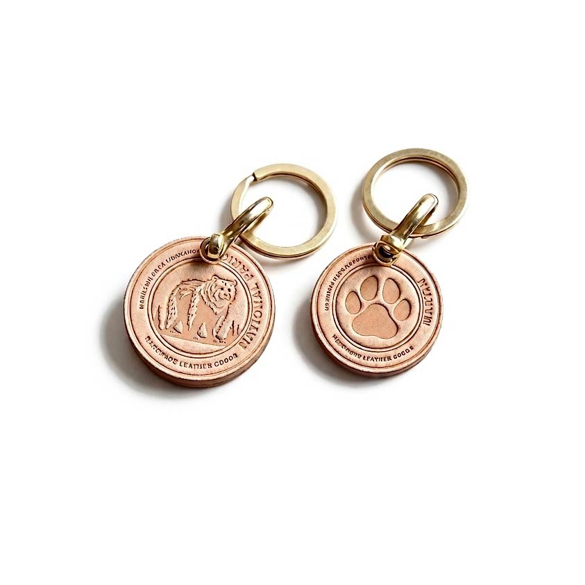 Two rose gold keychains with engraved designs on a white background