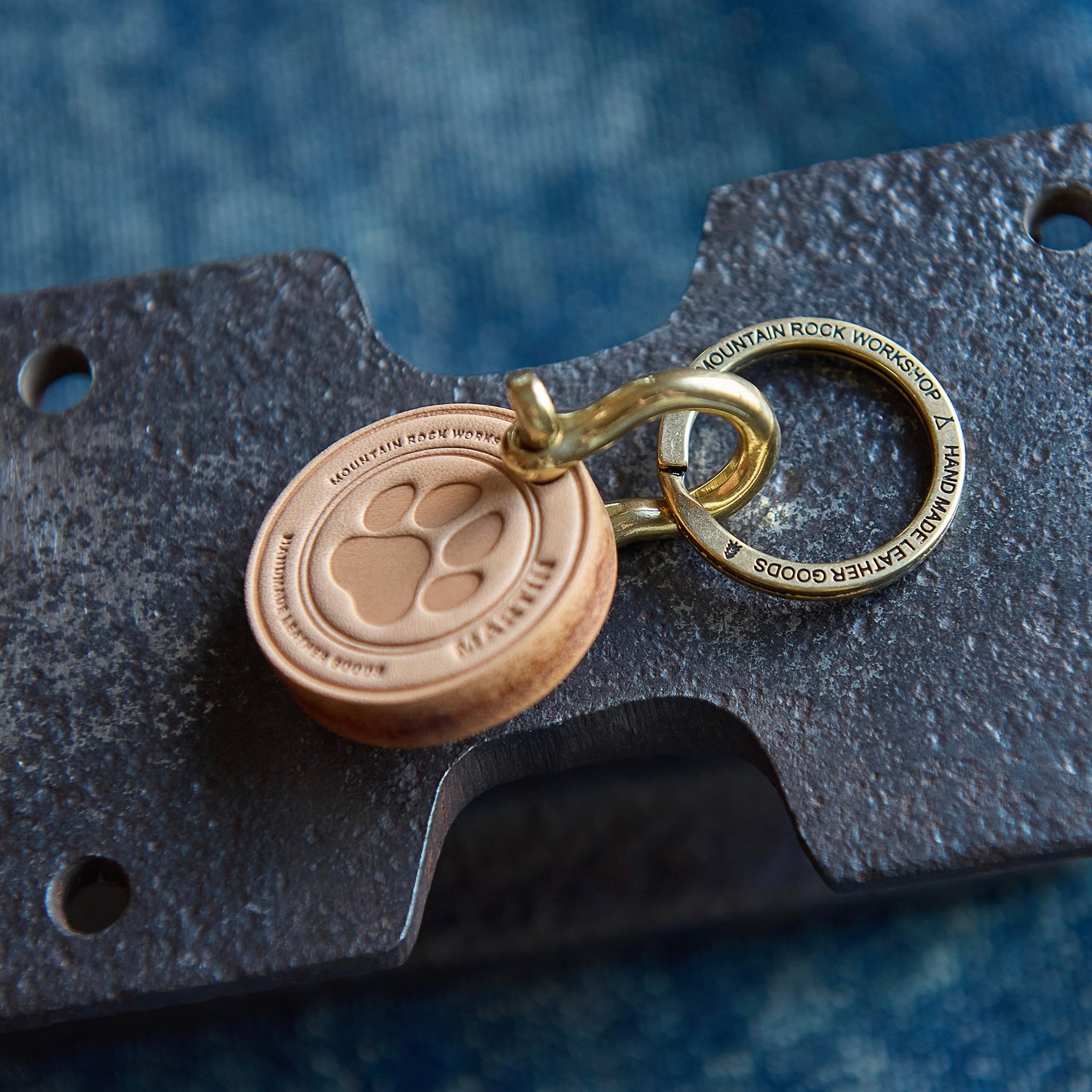 Keychain with paw print design attached to a leather wallet on a blue textured background