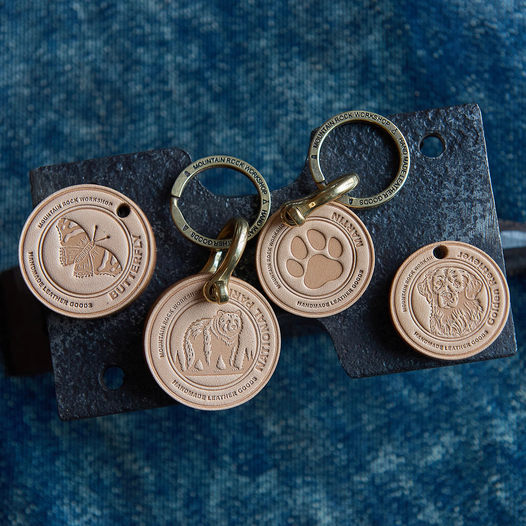 Set of bronze dog tags on a leather keychain against a blue denim background
