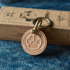 Bronze keychain with paw print design on a blue denim surface