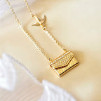 Gold necklace with a small bag pendant on a light background