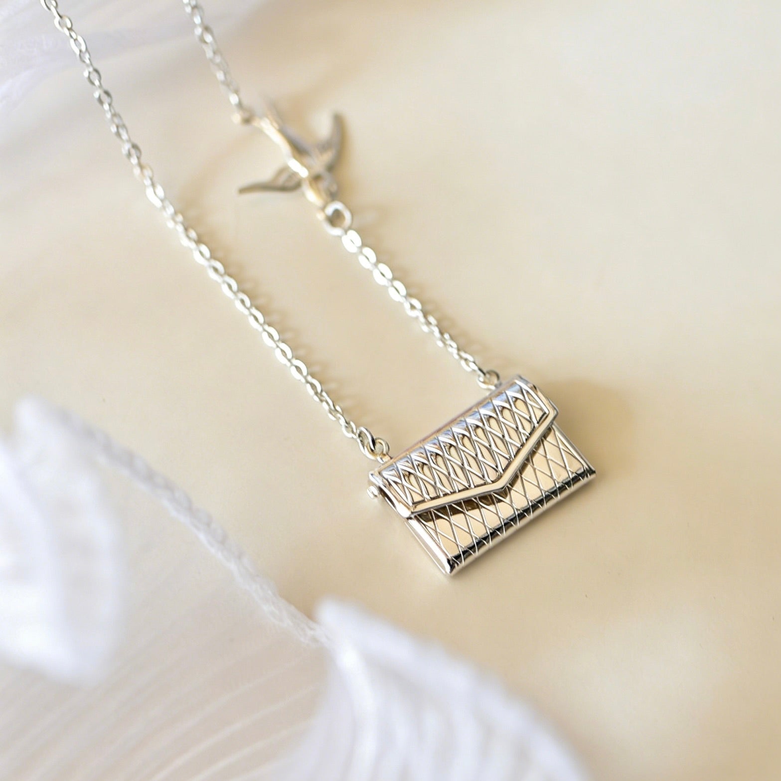 Silver necklace with a geometric pendant on a light background