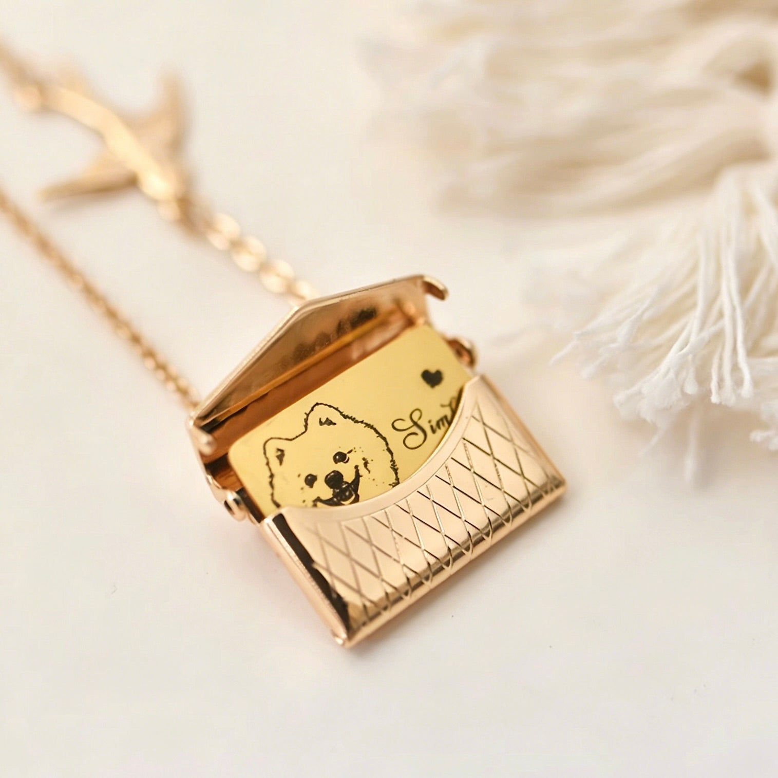 Gold necklace with a pendant featuring a dog's face and engraved text on a soft white background.