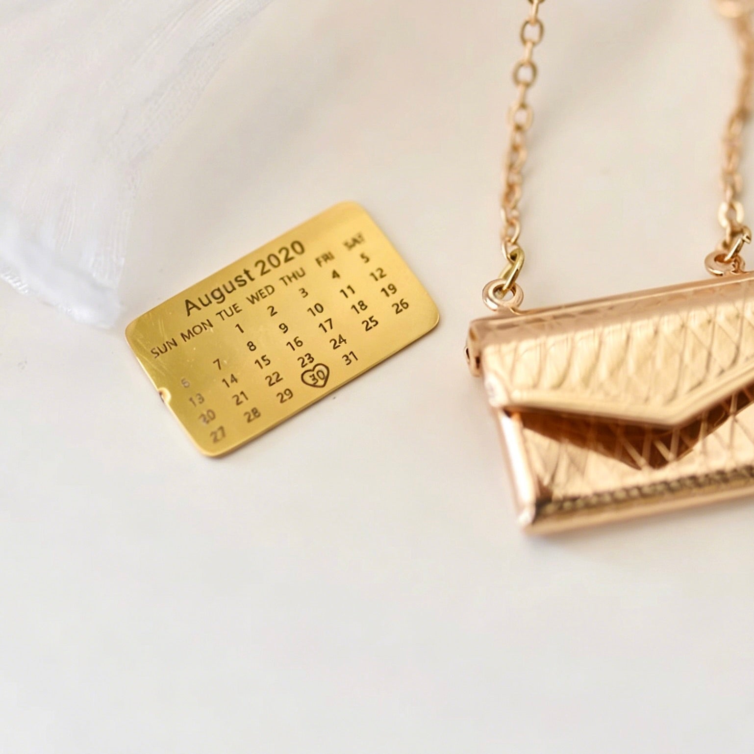 Gold necklace with a calendar pendant on a white background