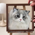 Framed picture of a fluffy cat held by a hand on a light background