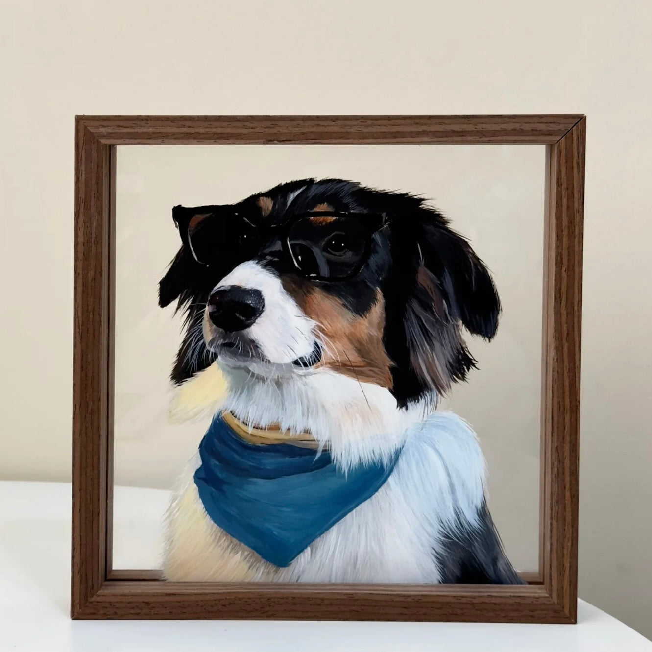Framed portrait of a dog with a blue bandana on a beige background