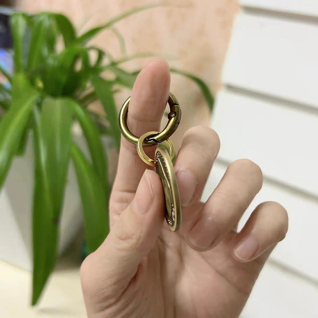 Gold ring with a unique design worn on a finger, with a plant in the background.
