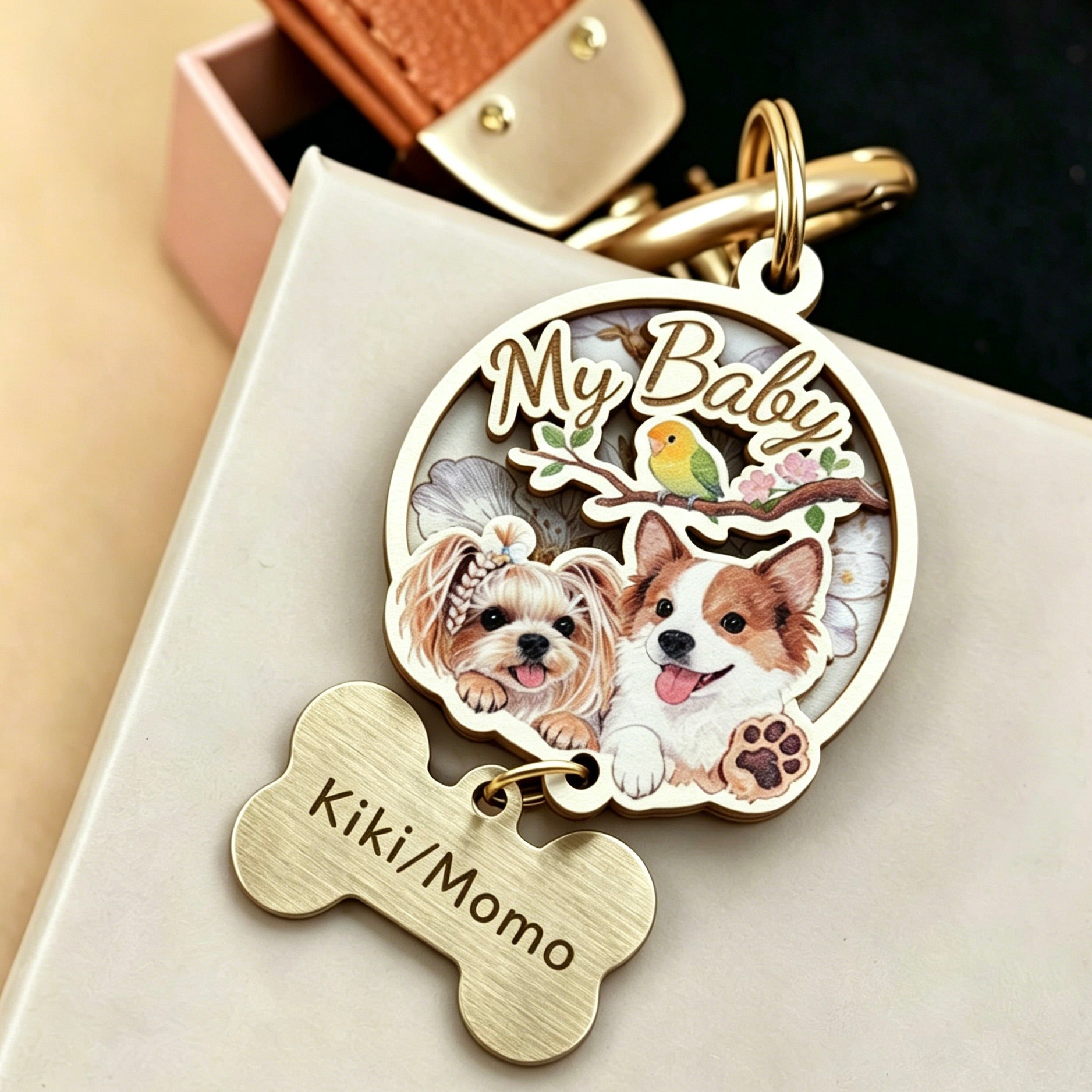 A close-up shot of a custom 3D wooden pet portrait keychain featuring a detailed relief of two dogs and a small bird with the text "My Baby". Perfect as a multi-pet memorial keepsake or personalized pet loss gift, it features premium gold hardware and a hanging bone tag engraved with the names "Kiki/Momo".