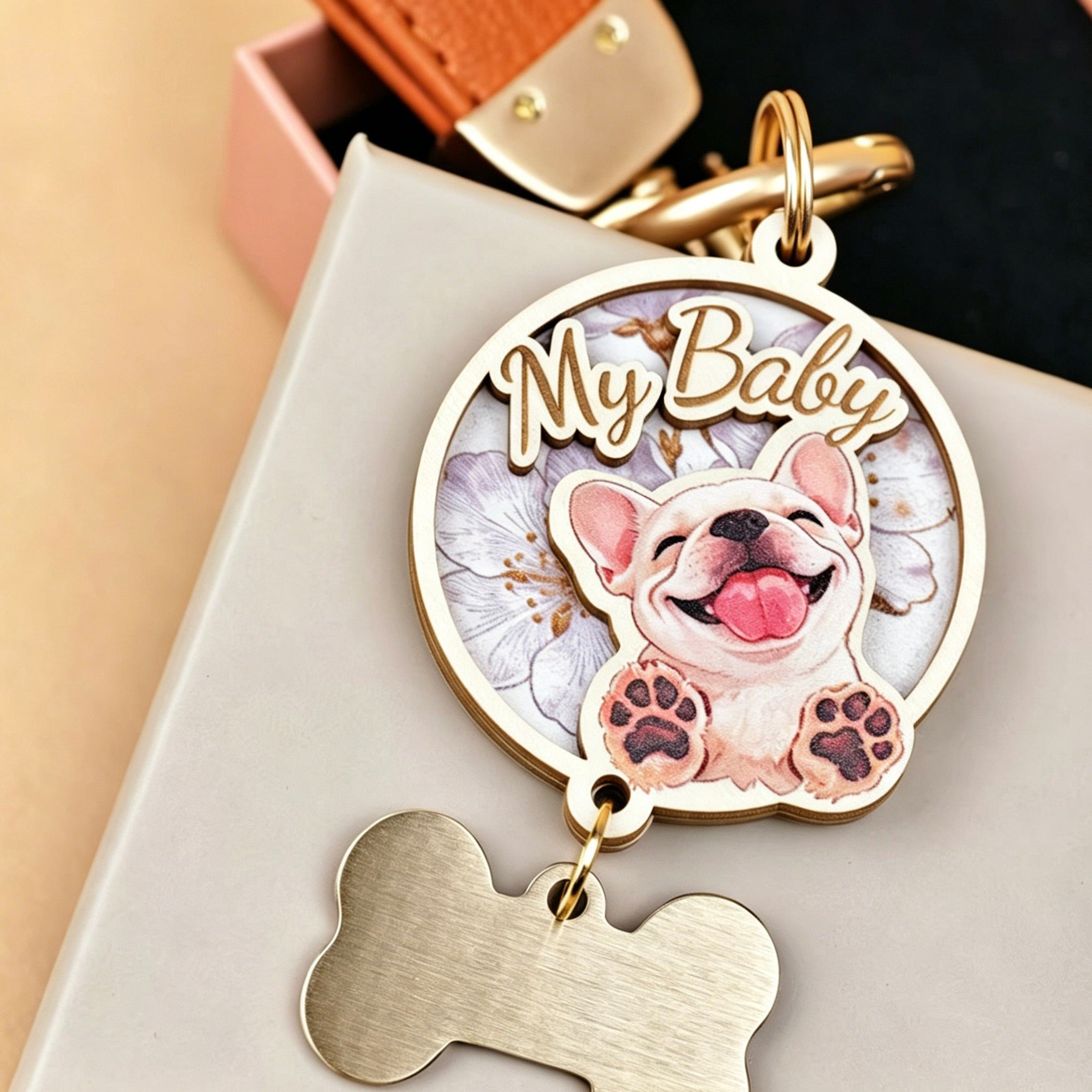 A close-up shot of a custom 3D wooden pet portrait keychain designed as a memorial keepsake, featuring a realistic 3D relief of a smiling white French Bulldog with the text "My Baby". This personalized pet loss gift includes a premium brown leather strap, gold hardware, and a hanging metal bone tag ready for custom name engraving.