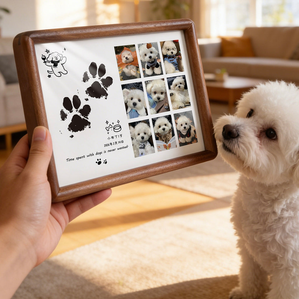 Person holding a framed photo collage of a dog with paw prints in a living room.