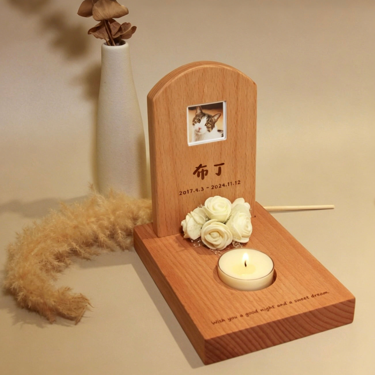 Wooden pet memorial with photo, flowers, and candle on a neutral background