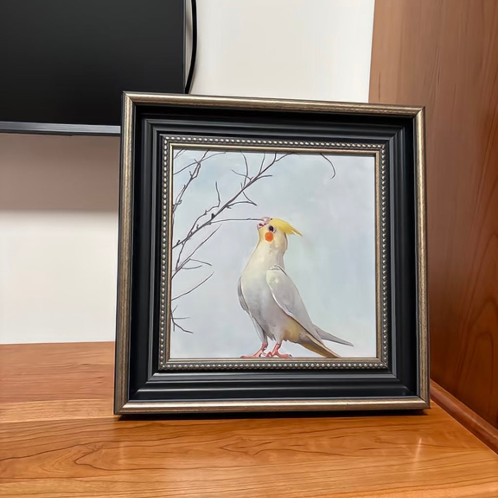 Framed artwork of a cockatiel on a wooden surface
