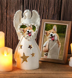 Decorative angel figurine with a heart-shaped cutout of a dog, next to a framed photo of a dog on a wooden surface.