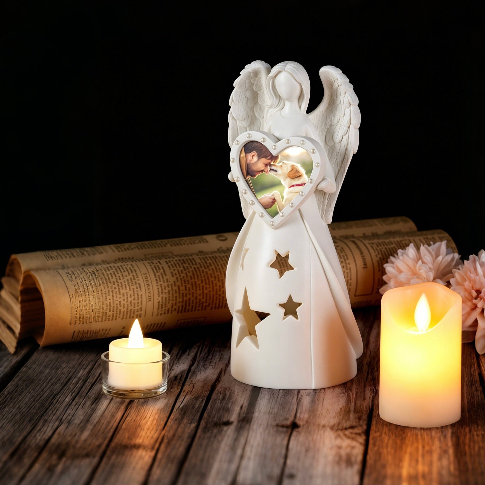 White angel figurine with heart-shaped photo frame on a wooden surface with candles and flowers.